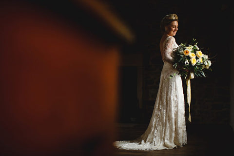 Bride holding a bouquet in a moodily lit room