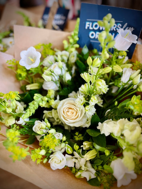 Bouquet of white and green flowers with a visible brand name on a cardboard box.